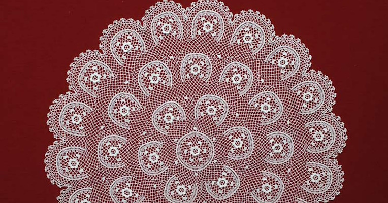 Gros plan sur un détail d'une broderie finement réalisée, avec une structure délicate en demi-cercle.