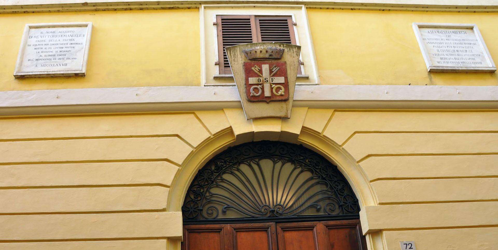 Dettaglio della facciata di Palazzo Lepri a Bevagna, con stemma centrale, portale ad arco e lunetta in ferro battuto.