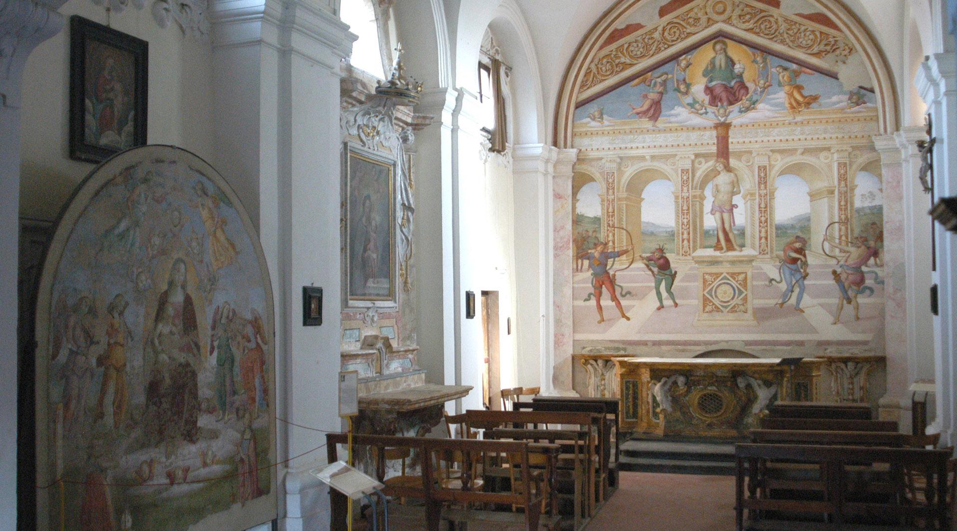Vista interna della chiesa: sulla parete sinistra si trova una tela raffigurante la Madonna delle Grazie, mentre al centro della navata sono disposte le panche per i fedeli. Sullo sfondo, dietro l'altare, è visibile il capolavoro del Perugino, "Il Martirio di San Sebastiano".