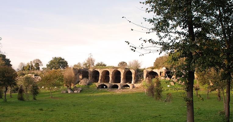 Vestiges monumentaux des grandes substructions d’Ocriculum, avec des arcades taillées dans la roche et une végétation environnante