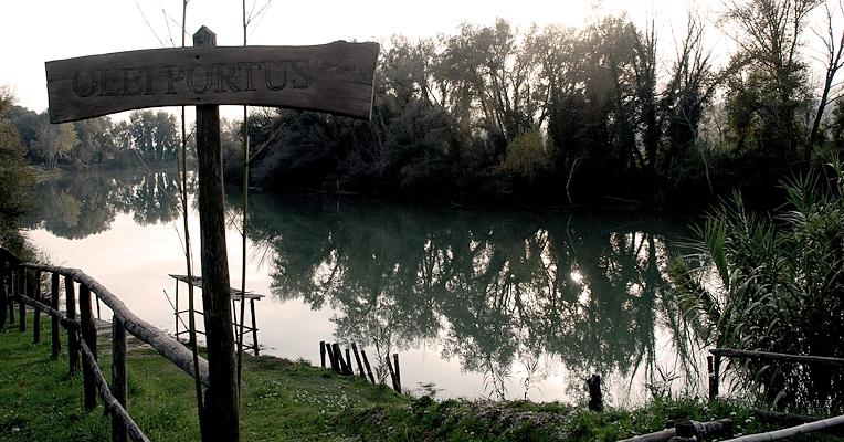 Veduta sul Tevere presso Ocriculum, con insegna in legno del Porto dell’Olio e alberi riflessi nell’acqua