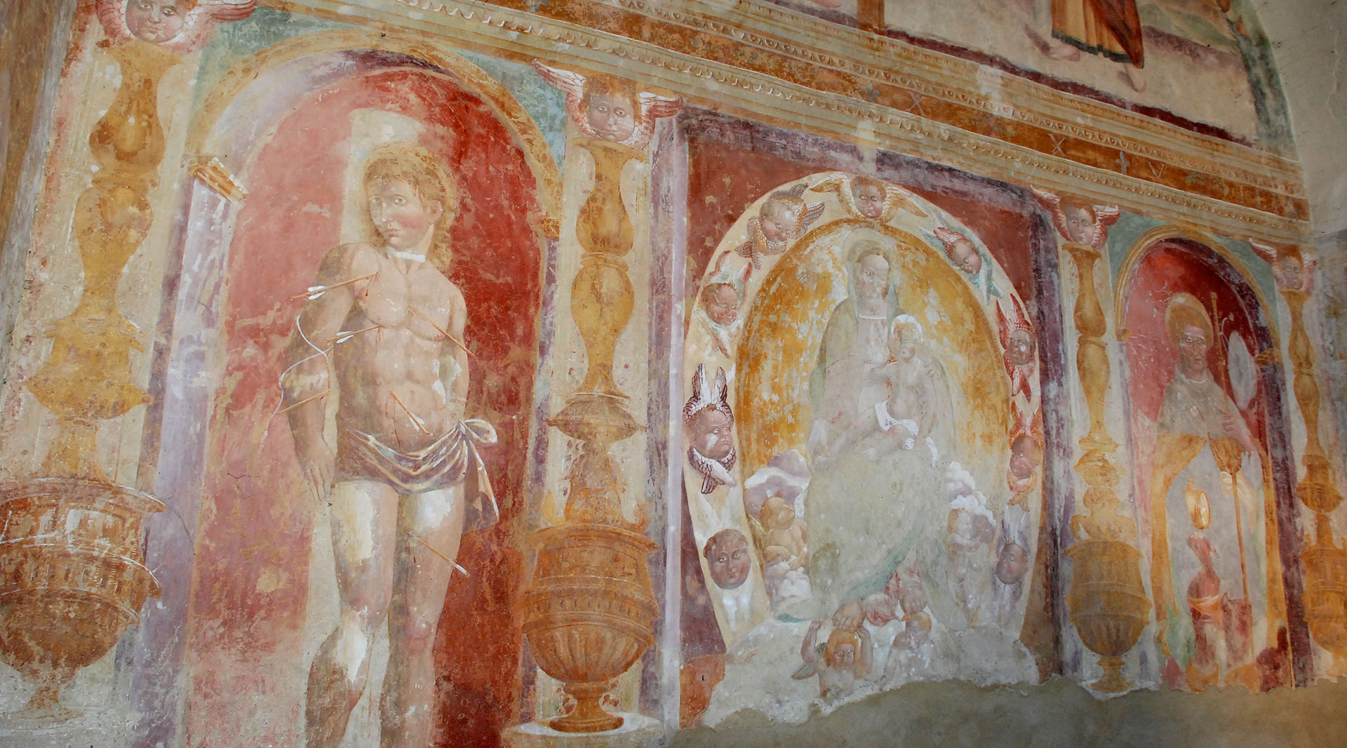 Sakrale Fresken in der Kapelle San Rocco mit Heiligenfiguren in gemalten Nischen und mittelalterlichen Dekorationen.