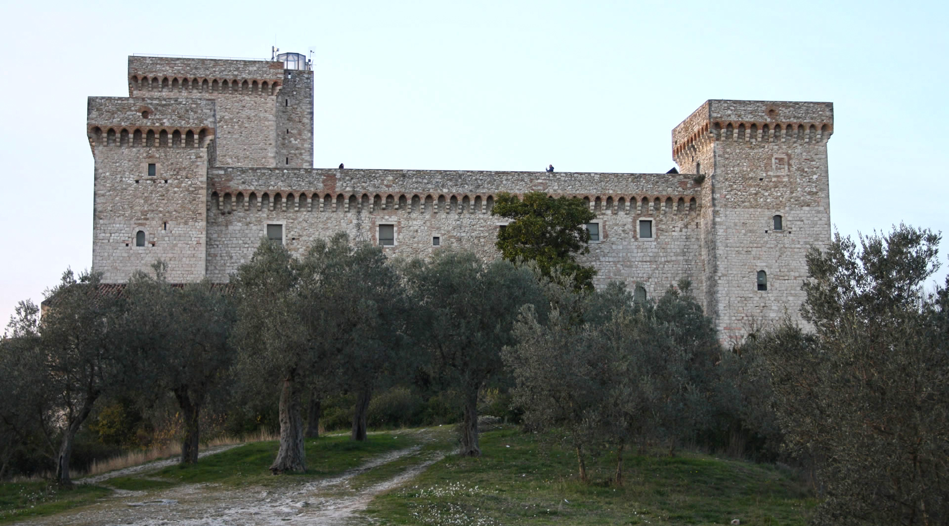 Frontansicht der Rocca von Narni, einer imposanten mittelalterlichen Steinburg, umgeben von Olivenbäumen