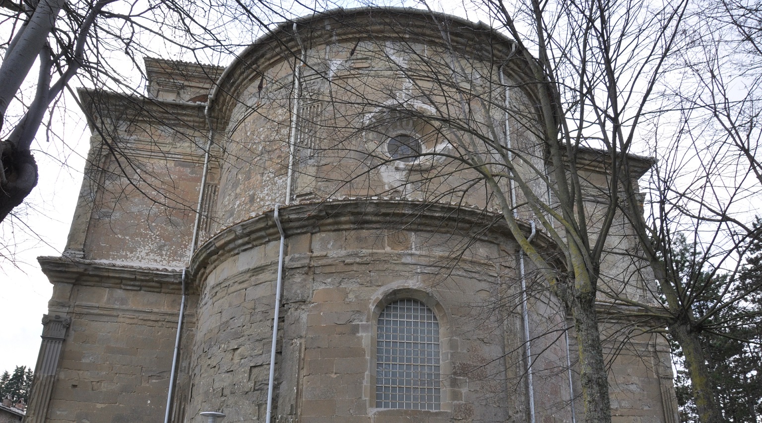 Rear facade of the Sanctuary of Madonna dei Miracoli, featuring a large central window and a skylight positioned at the top, allowing natural light to enter the building.
