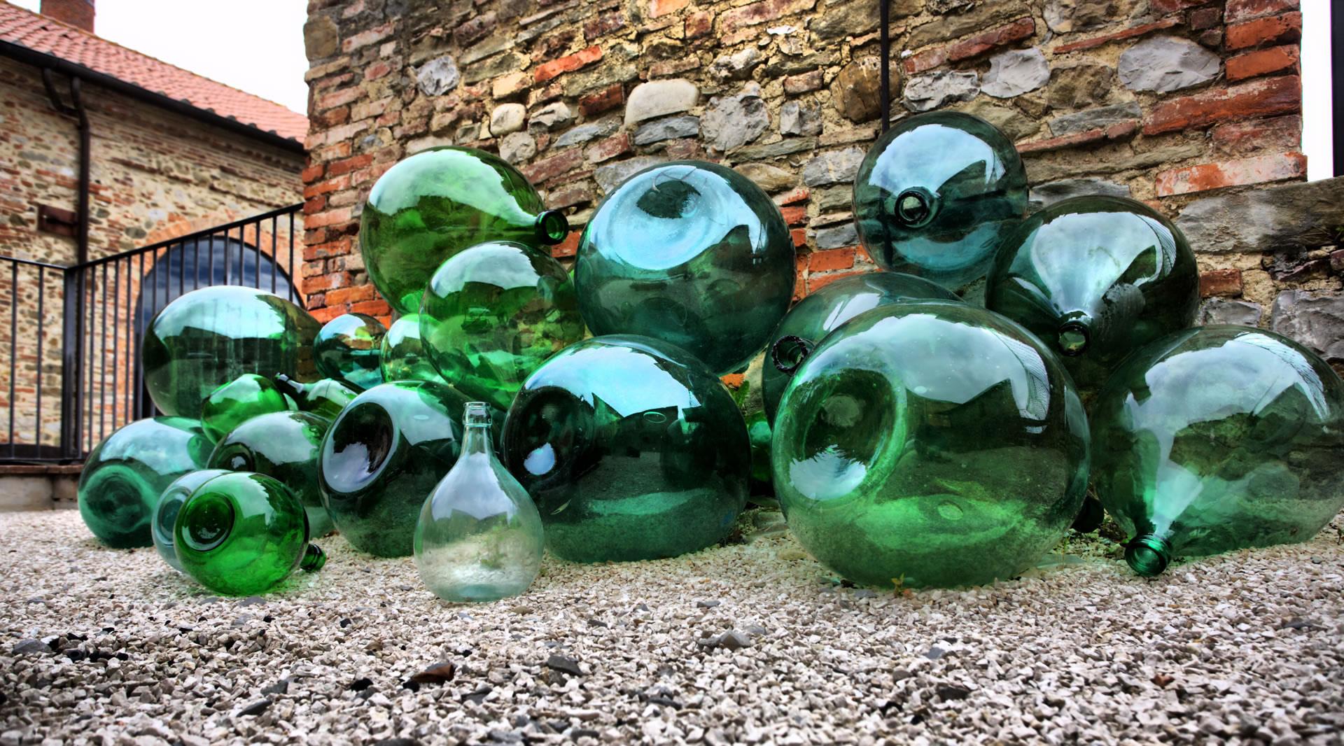 The outdoor exhibition showcases a collection of glass artifacts, featuring a variety of demijohns and bottles, a testament to ancient craftsmanship.