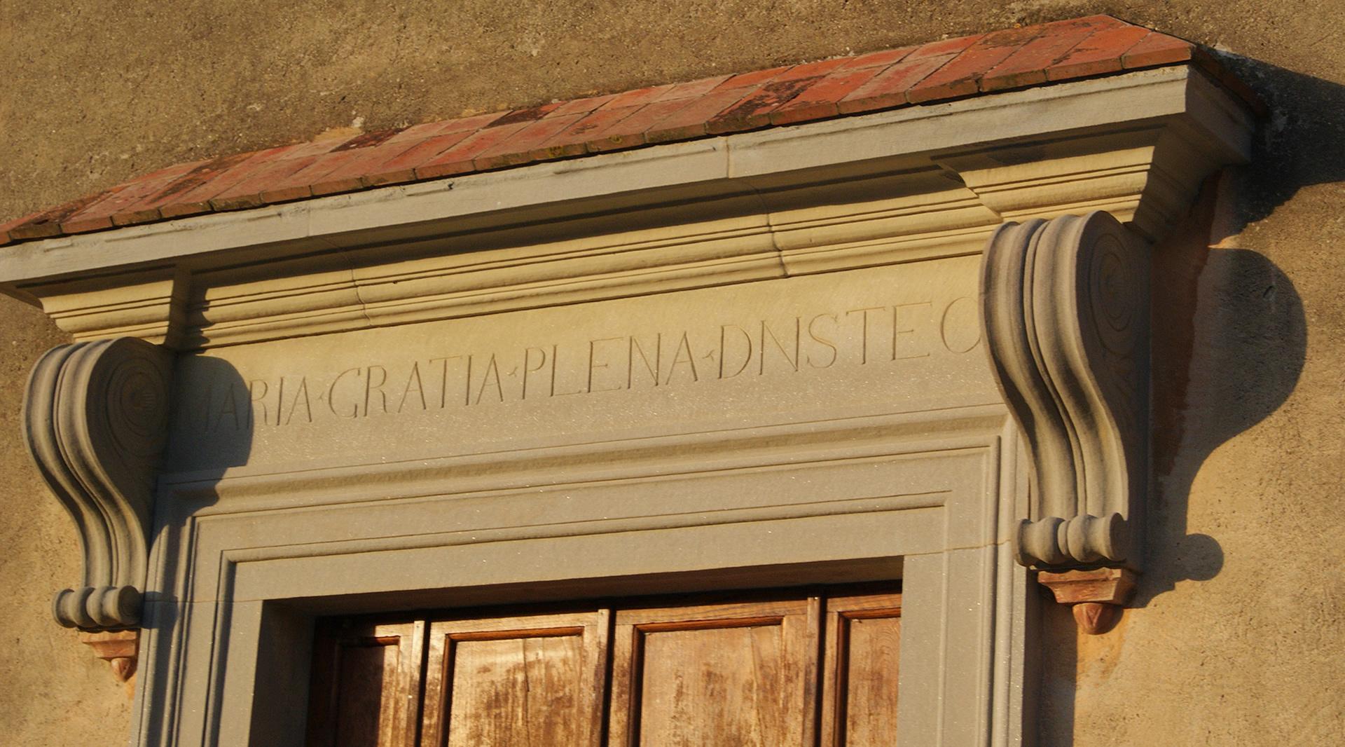 Stone portal with an inscription above a wooden door, decorated with side volutes.