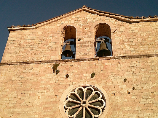 Detail of the bell gable with two bells and the stone rose window of the Church of San Giovanni in Vallo di Nera.