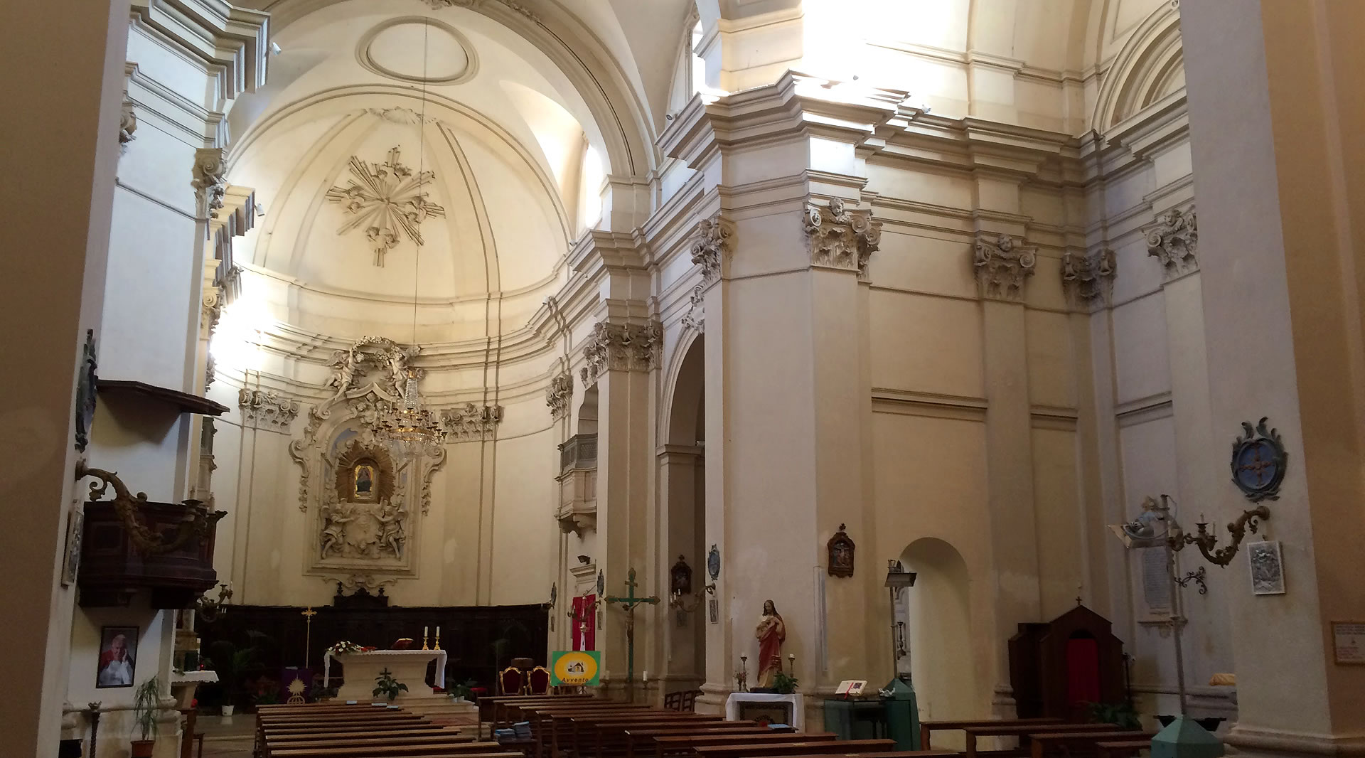 Innenraum der Kirche von Giove mit hellem Kirchenschiff, verzierten Säulen, Altar und freskierten Gewölben.