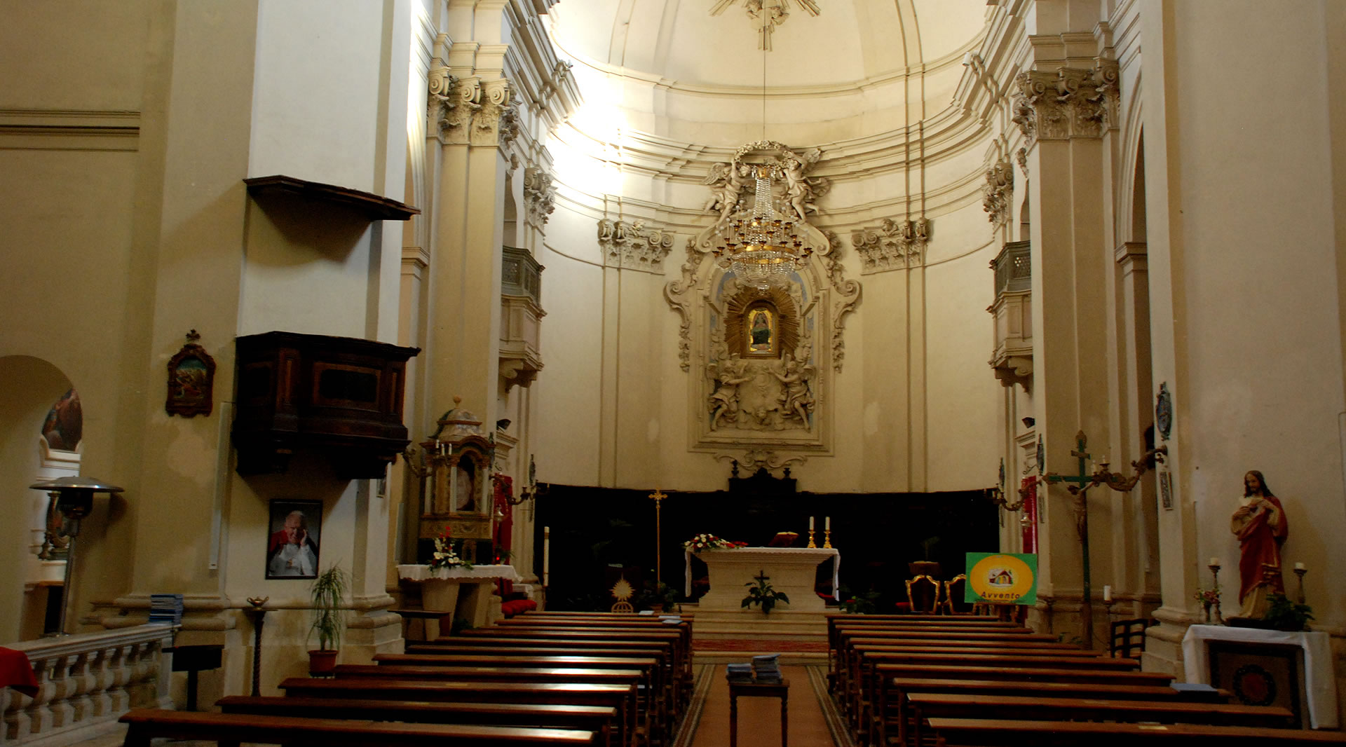 Mittelschiff der Kirche von Giove mit barockem Altar, Holzbänken und Stuckverzierungen.