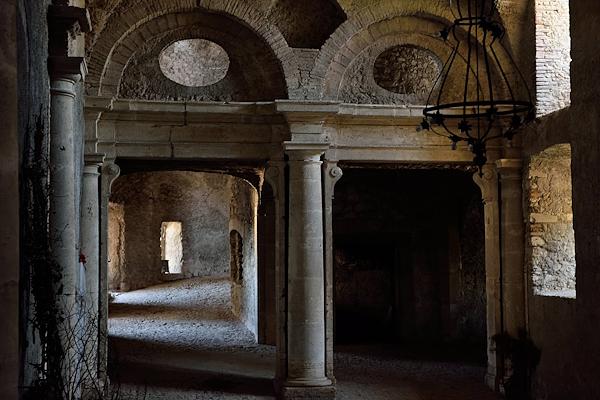 Interior of the Castle of Giove with stone arches, columns and light entering through a window.