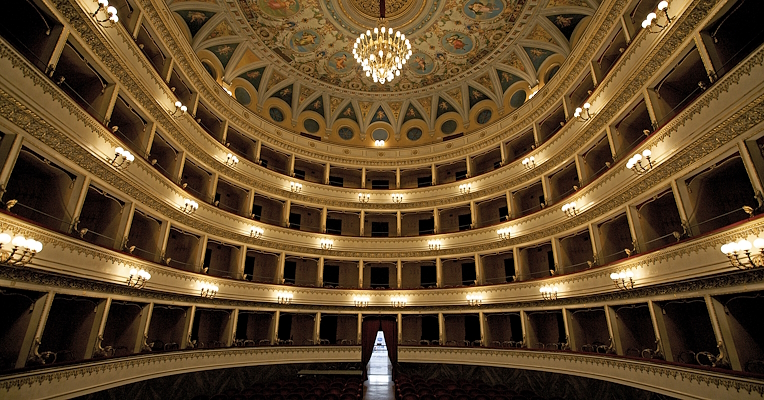 Interno del Teatro Mancinelli di Orvieto: elegante sala con cinque ordini di palchi, affreschi sul soffitto e lampadario.