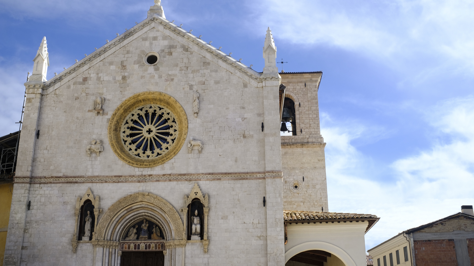 Facade of the Basilica of Saint Benedict in Norcia with central rose window, Gothic details and bright sky