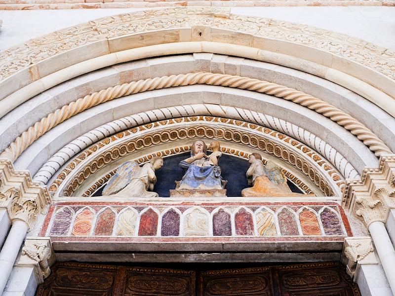 Dettaglio del portale con sculture sacre e decorazioni policrome sopra l’ingresso della basilica