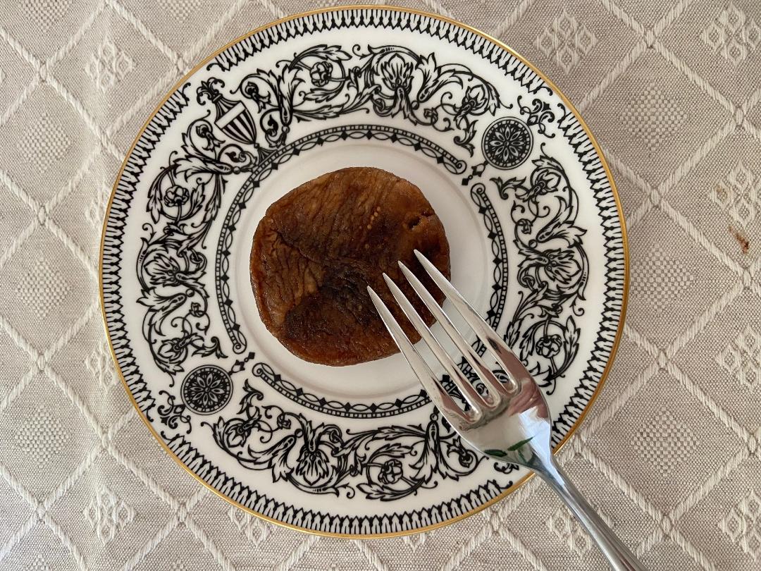 A stuffed dried fig on a black-and-white decorated porcelain plate, with a fork beside it.