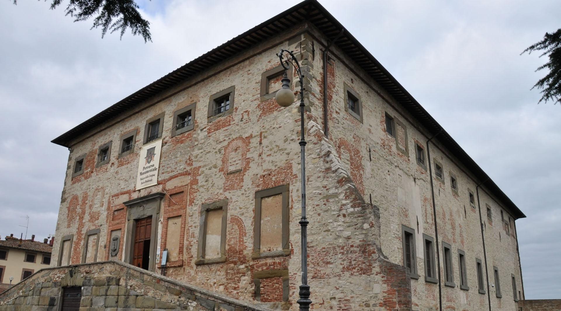 Corner view of the Palazzo della Corgna in Castiglione del Lago, with exposed brickwork, external staircase and historic street lamp in the foreground.