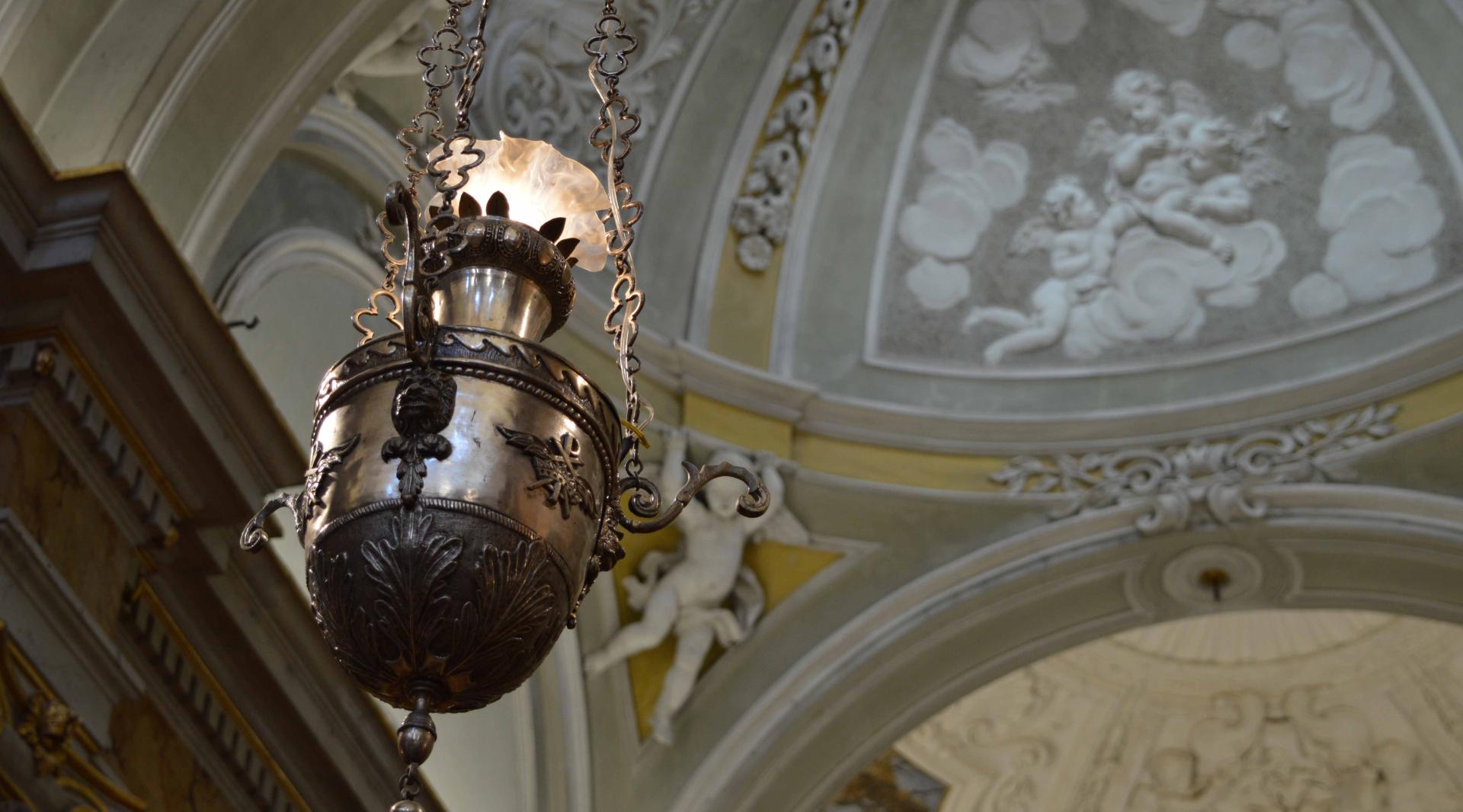 Detail of a chandelier inside the church, with bas-reliefs of angels decorating the background.