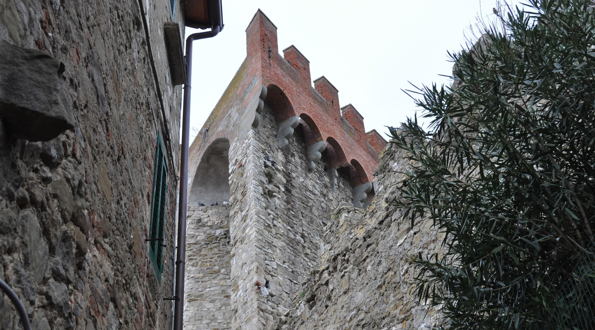 Dettaglio della Torre della Rocca di Passignano, evidenziando la sua caratteristica forma triangolare in muratura che si staglia nel paesaggio.