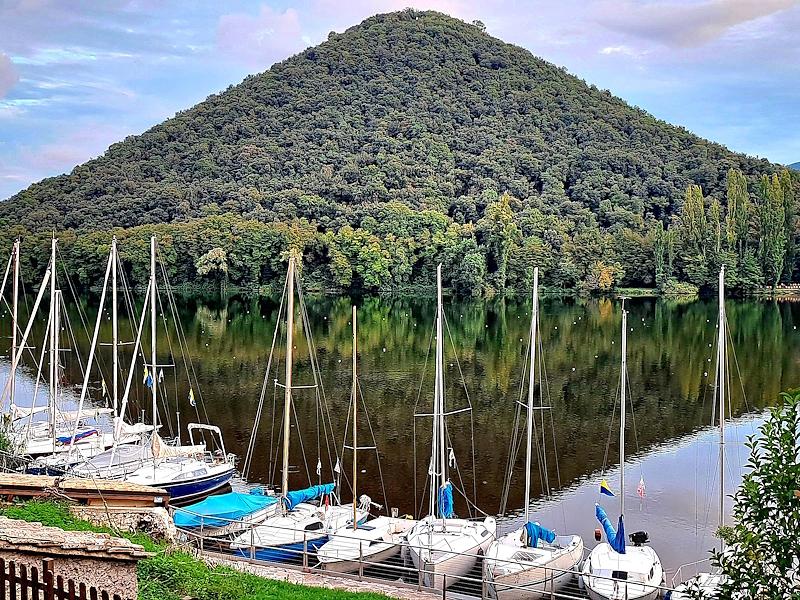 Sailboats on Lake Piediluco with the pyramid-shaped profile of Mount Caperno reflected in the water.