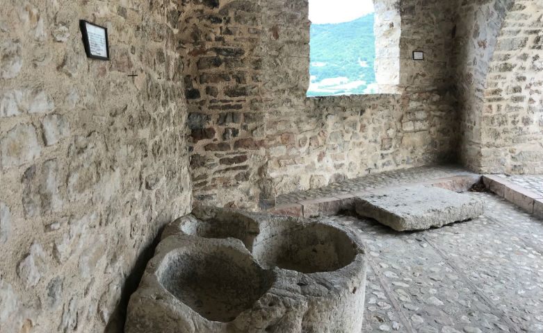 Alte Steingefäße in einem historischen Gebäude in Monteleone di Spoleto mit Blick auf das umliegende Tal.
