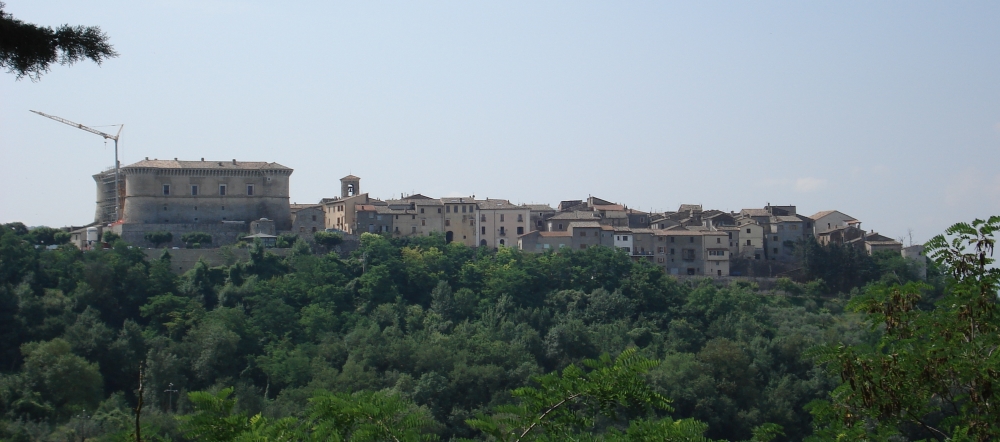 Panorama der Rocca von Alviano und des mittelalterlichen Dorfes, gelegen auf einem grünen Hügel, umgeben von umbrischen Wäldern.