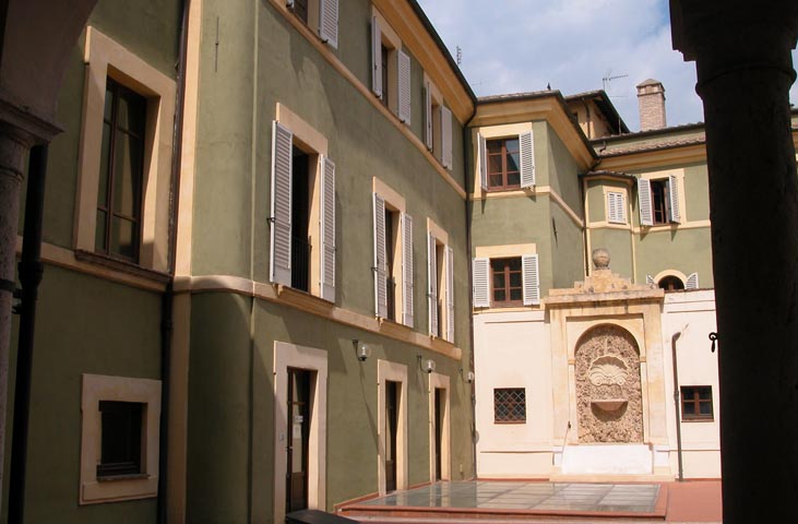 Innenhof des Palazzo Gazzoli in Terni mit blassgrüner Fassade und dekorativem Steinbrunnen