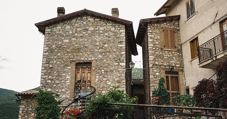 Case in pietra con balconi fioriti nel centro storico di Poggiodomo