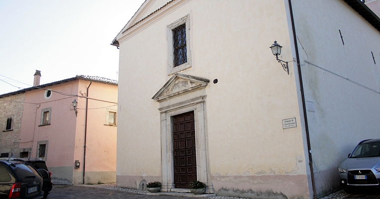 Facciata della Chiesa di San Carlo Borromeo a Poggiodomo, con portale rinascimentale e finestra con grata.
