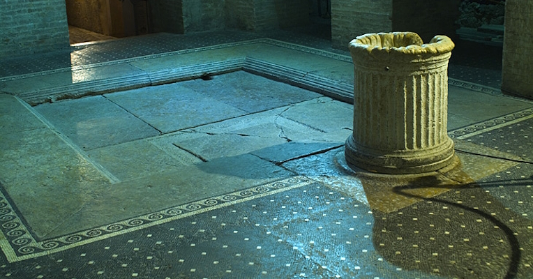 Interno della Casa Romana a Spoleto con pavimento a mosaico in tessere nere e bianche, vasca centrale in pietra e colonna scanalata.