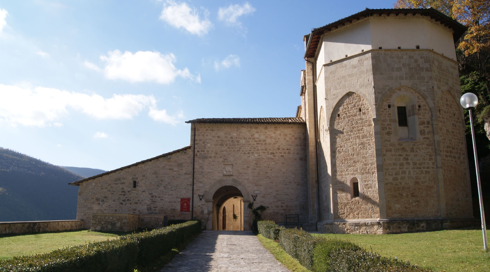 Stone façade of the Abbey of Sant’Eutizio, lit by the sun on a clear day.