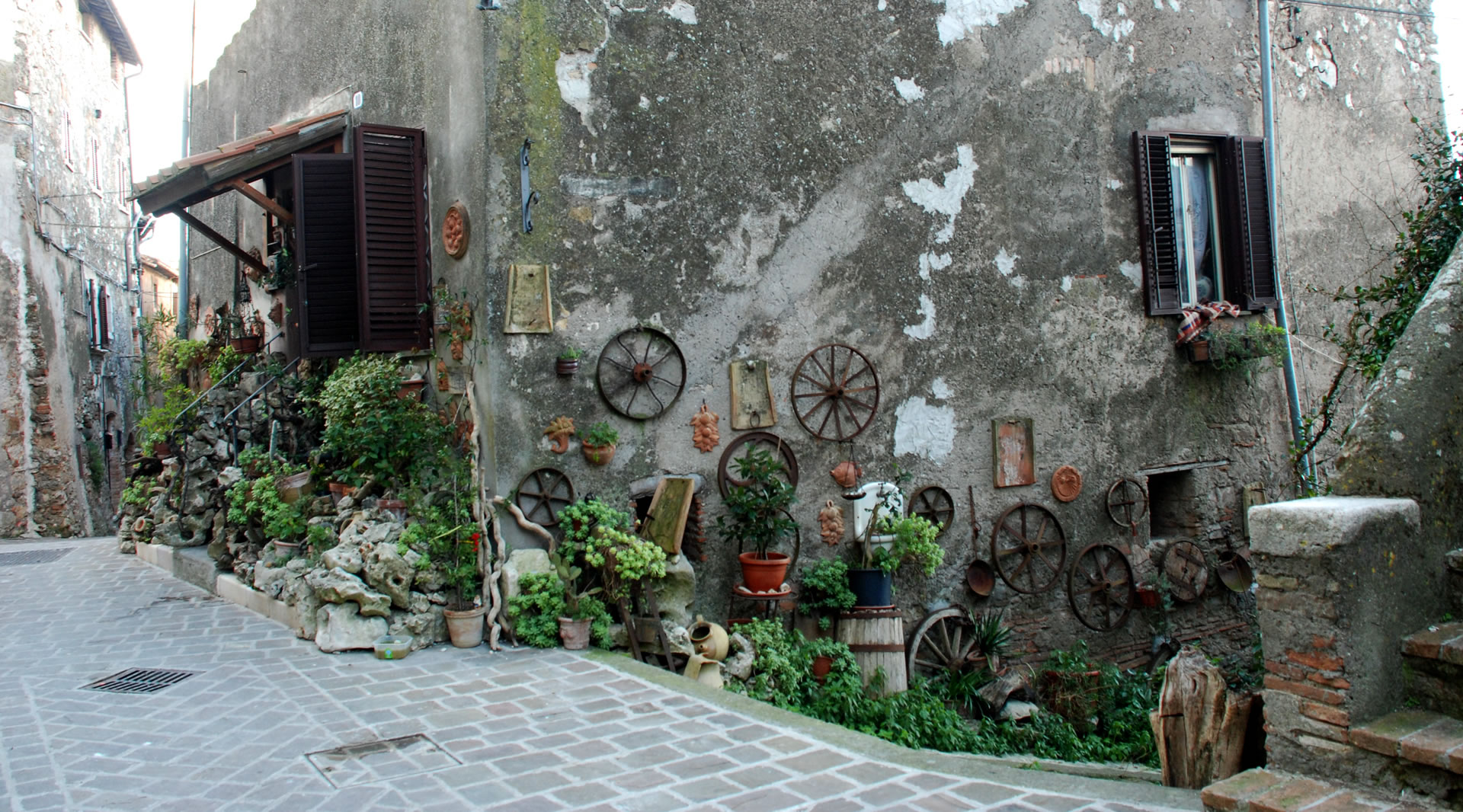 Gasse in Giove mit Steinhäusern, geschmückt mit Töpfen, Pflanzen und alten Werkzeugen