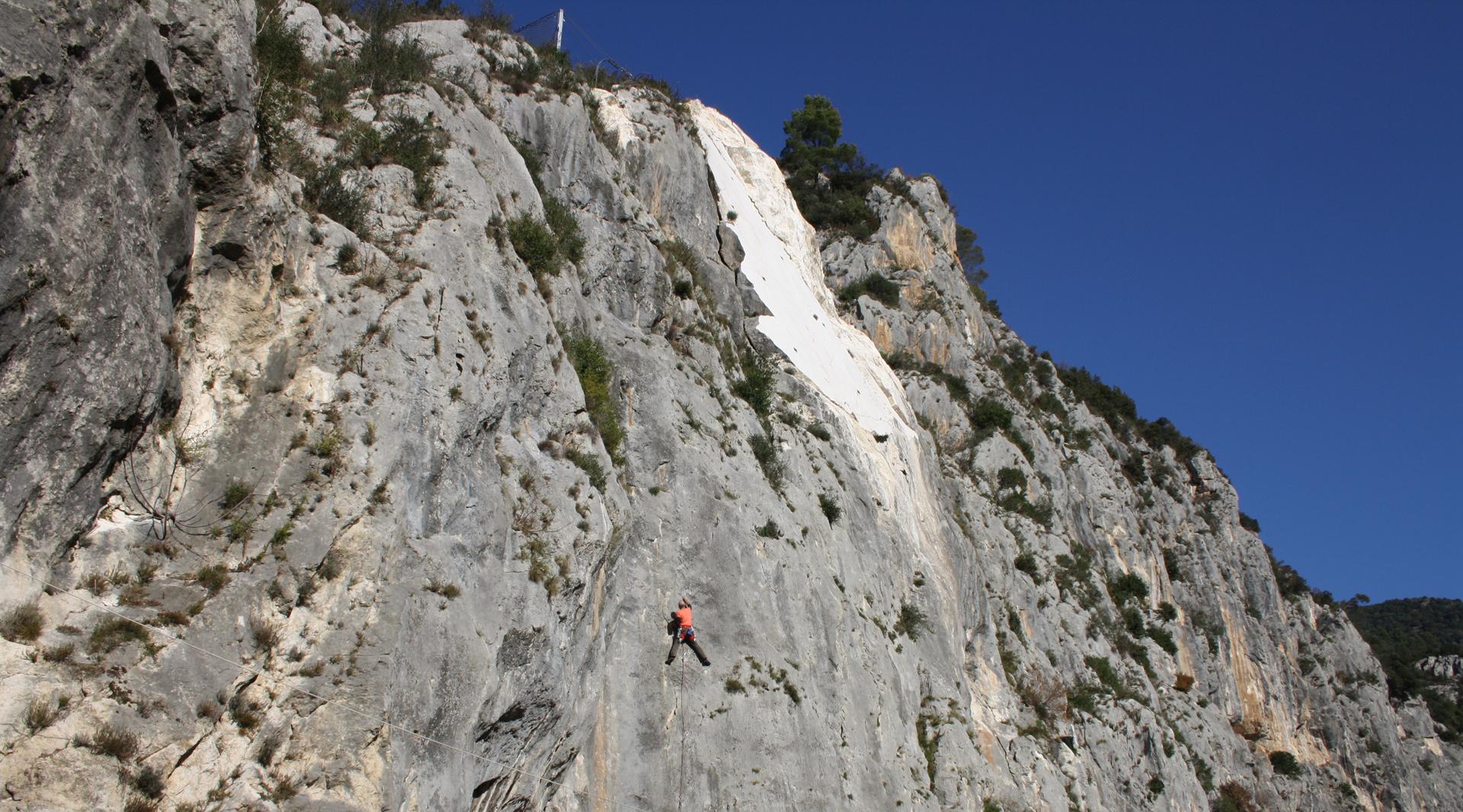Arrampicatore sulla falesia di Ferentillo, su parete rocciosa verticale immersa nel paesaggio della Valnerina.