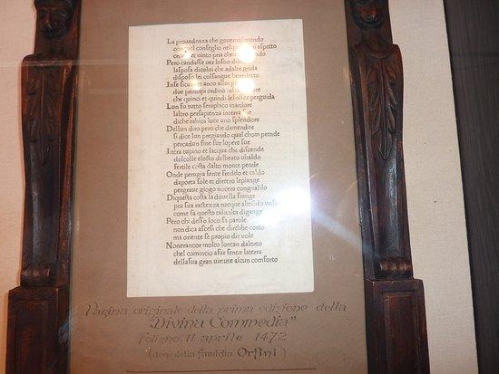 Pagina della prima edizione della Divina Commedia in una teca, con didascalia esplicativa e cornice in legno intagliato.