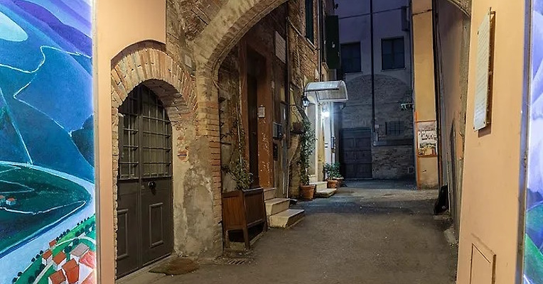 Malerische Gasse mit Backsteinbögen, historischen Mauern und bunten künstlerischen Verzierungen, in eine abendliche Atmosphäre getaucht.