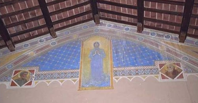 Fresko mit einer betenden Madonna im Zentrum, auf einem blauen Hintergrund mit Sternen verziert, flankiert von zwei Heiligenfiguren, unter einem Holzbalkendach.