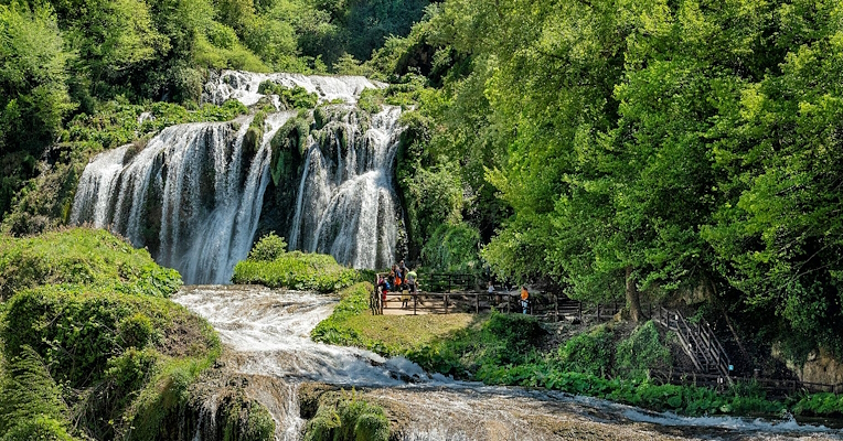 Marmore Falls surrounded by greenery with visitors on the scenic walkway