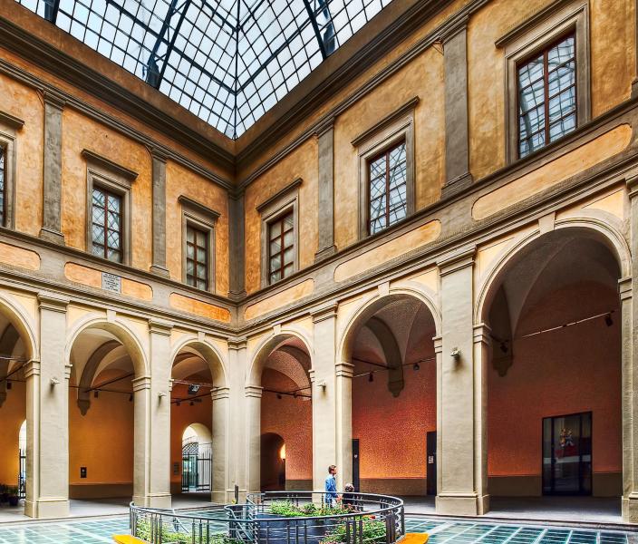 Cour intérieure du Palazzo Bufalini avec loggia à arcades, fenêtres encadrées de pierre et toiture vitrée.