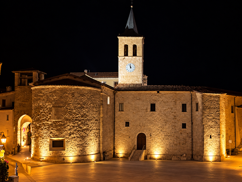 Night view of Castel Ritaldi, illuminated in the empty square beneath a dark sky.