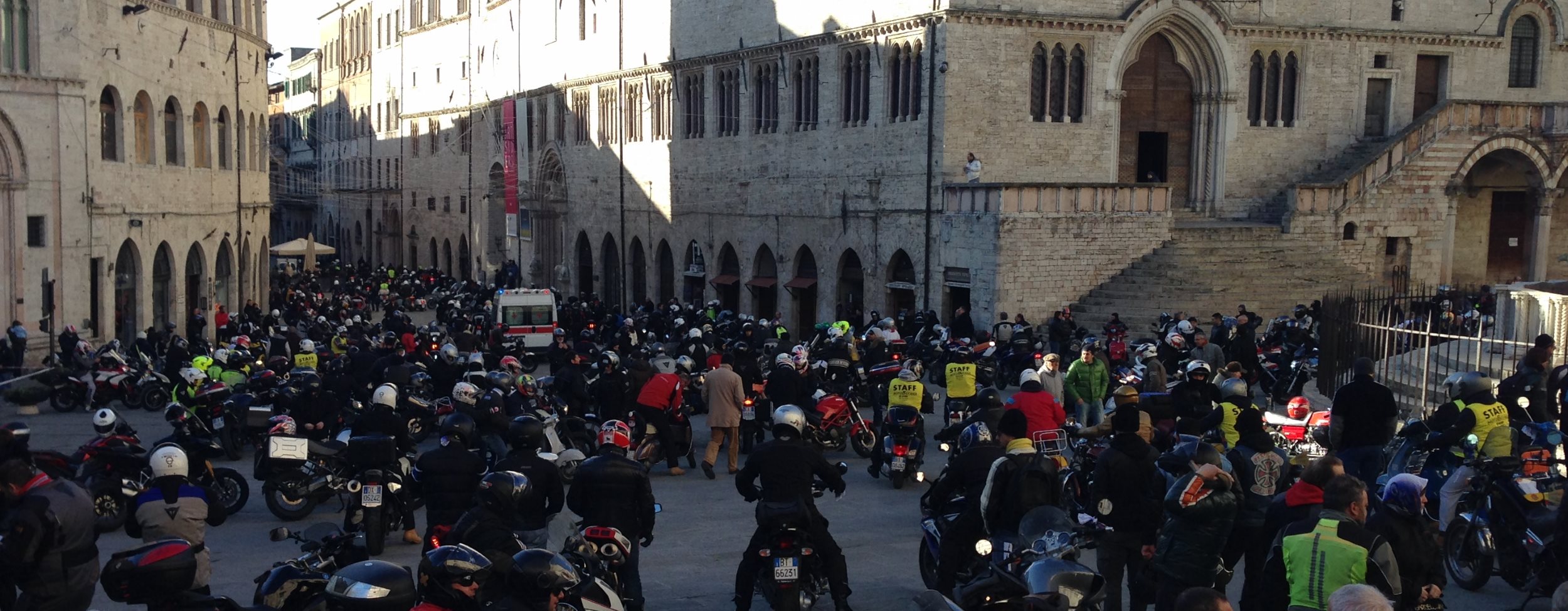 Piazza IV Novembre a Perugia affollata di motociclisti e moto durante un raduno; sullo sfondo, edifici storici.