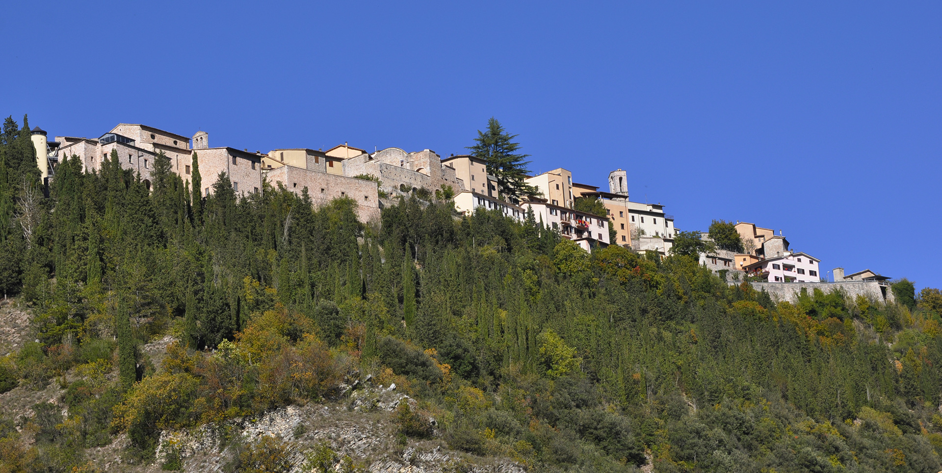 Vista panoramica dal basso di Cerreto di Spoleto, con il castello arroccato sulla collina circondato da un verde bosco