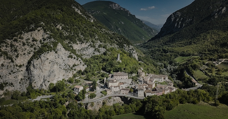 Vista aerea del borgo medievale di Triponzo, incastonato tra montagne verdi e vallate boscose