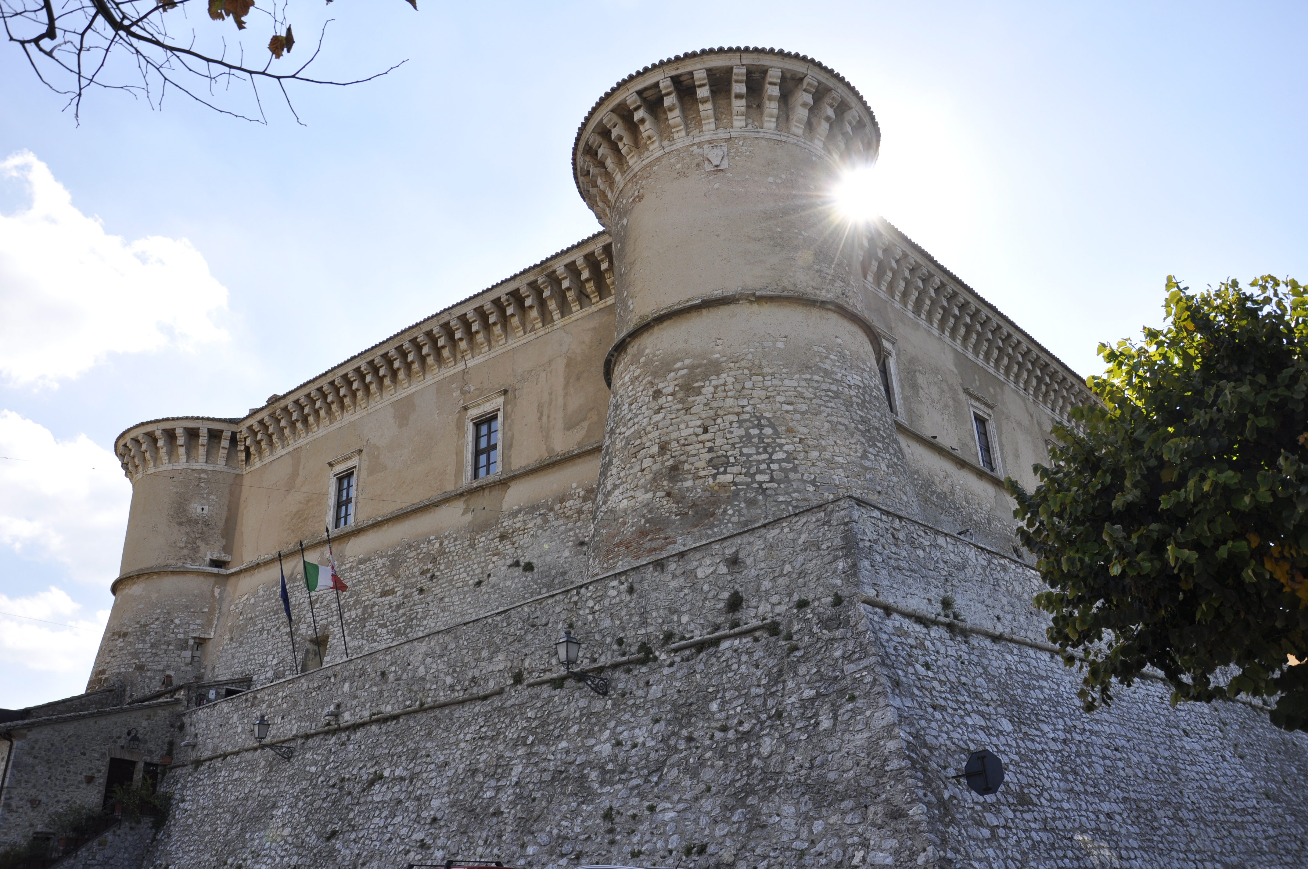 Die Rocca von Alviano im Vordergrund mit Zinnentürmen und Steinmauern, vom Sonnenlicht hinter ihren Strukturen erhellt.