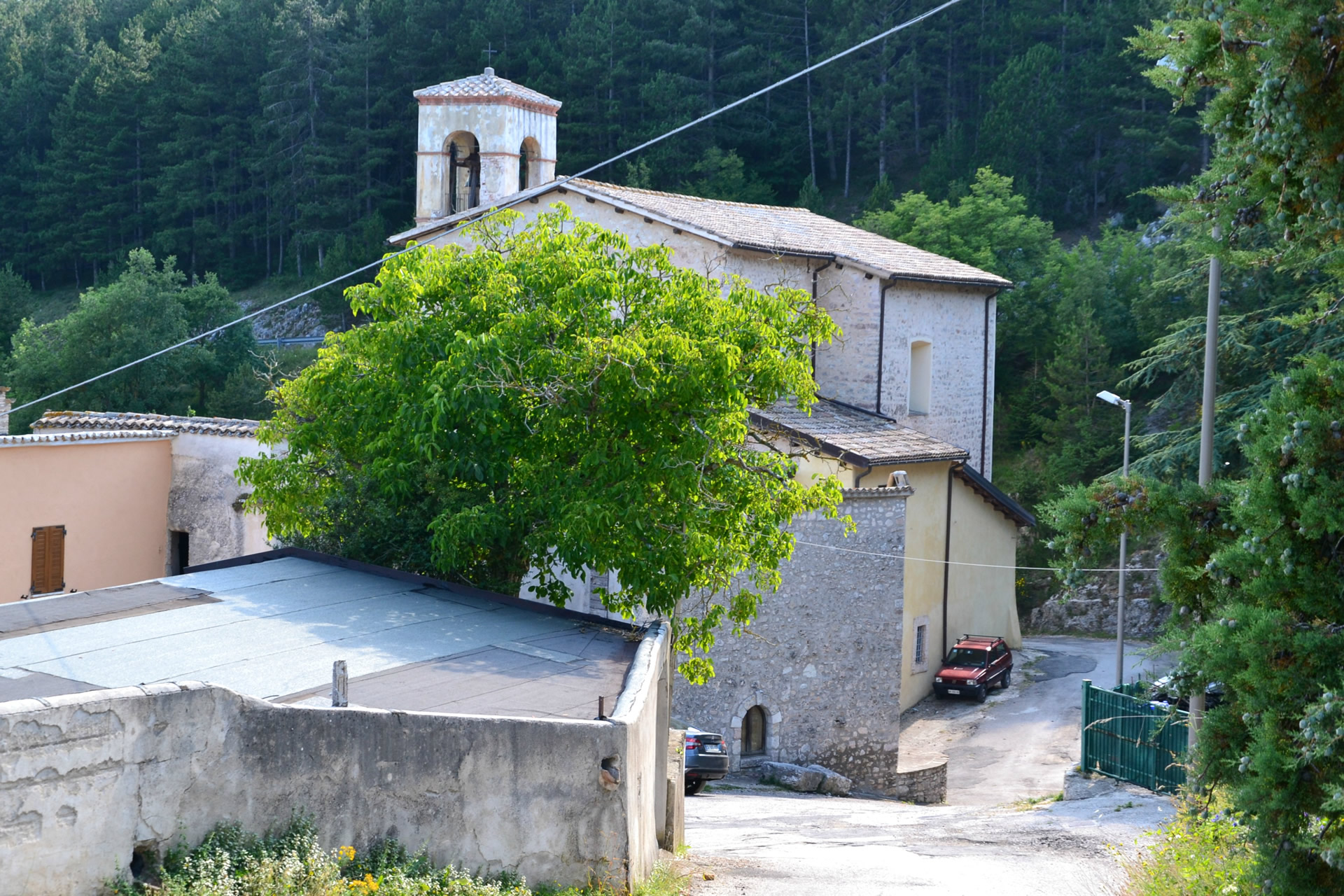 Chiesa in pietra del Santuario di Cancelli con campanile a vela, immersa nel verde ai margini del borgo.