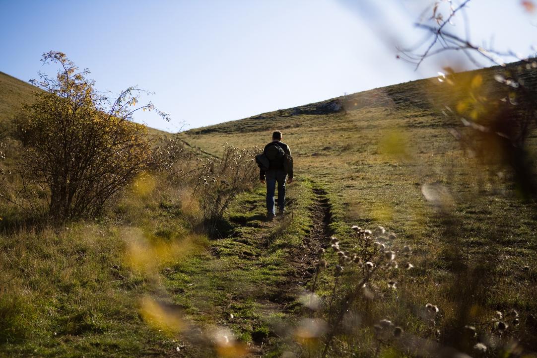 un uomo cammina in aperta montagna di Assisi con attrezzatura trekking