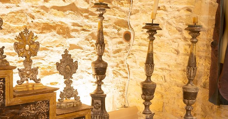 Una serie di candelabri e ostensori religiosi finemente lavorati a mano, con dettagli artigianali raffinati.