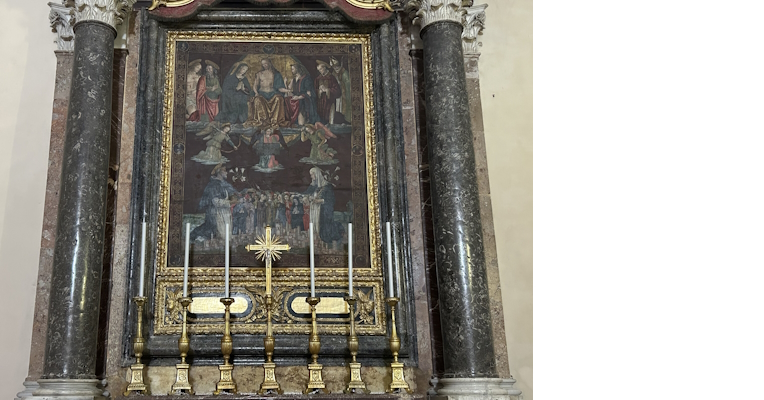 Framed altarpiece with dark marble columns, depicting sacred scenes and surrounded by golden candlesticks with a cross in the center.