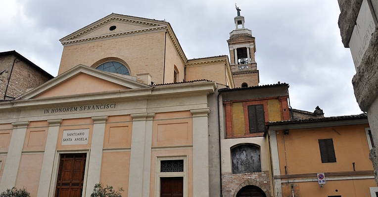 Facade of the Church of San Francesco in Foligno with a bell tower in the background, partial view of adjacent buildings.