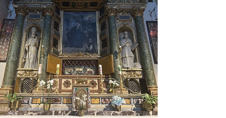 Altar decorated with statues of saints, central painting, green marble columns, and flowers on the sides in the Church of Santa Chiara.
