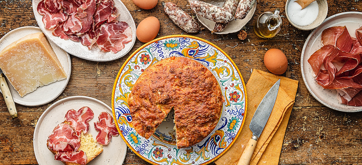 Tavola con torta di Pasqua su piatto di ceramica di Deruta, capocollo, pecorino e altra norcineria