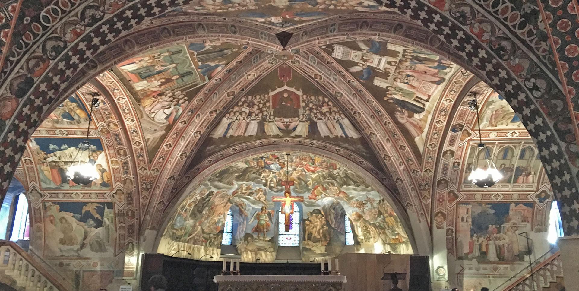Interno della Basilica Inferiore di San Francesco ad Assisi, con la volta riccamente affrescata. Gli affreschi raffigurano scene religiose. Il soffitto e le pareti sono finemente decorati con motivi gotici.