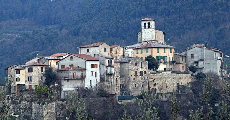 Veduta del borgo medievale di Papigno, con case in pietra e campanile, immerso tra colline boscose umbre.